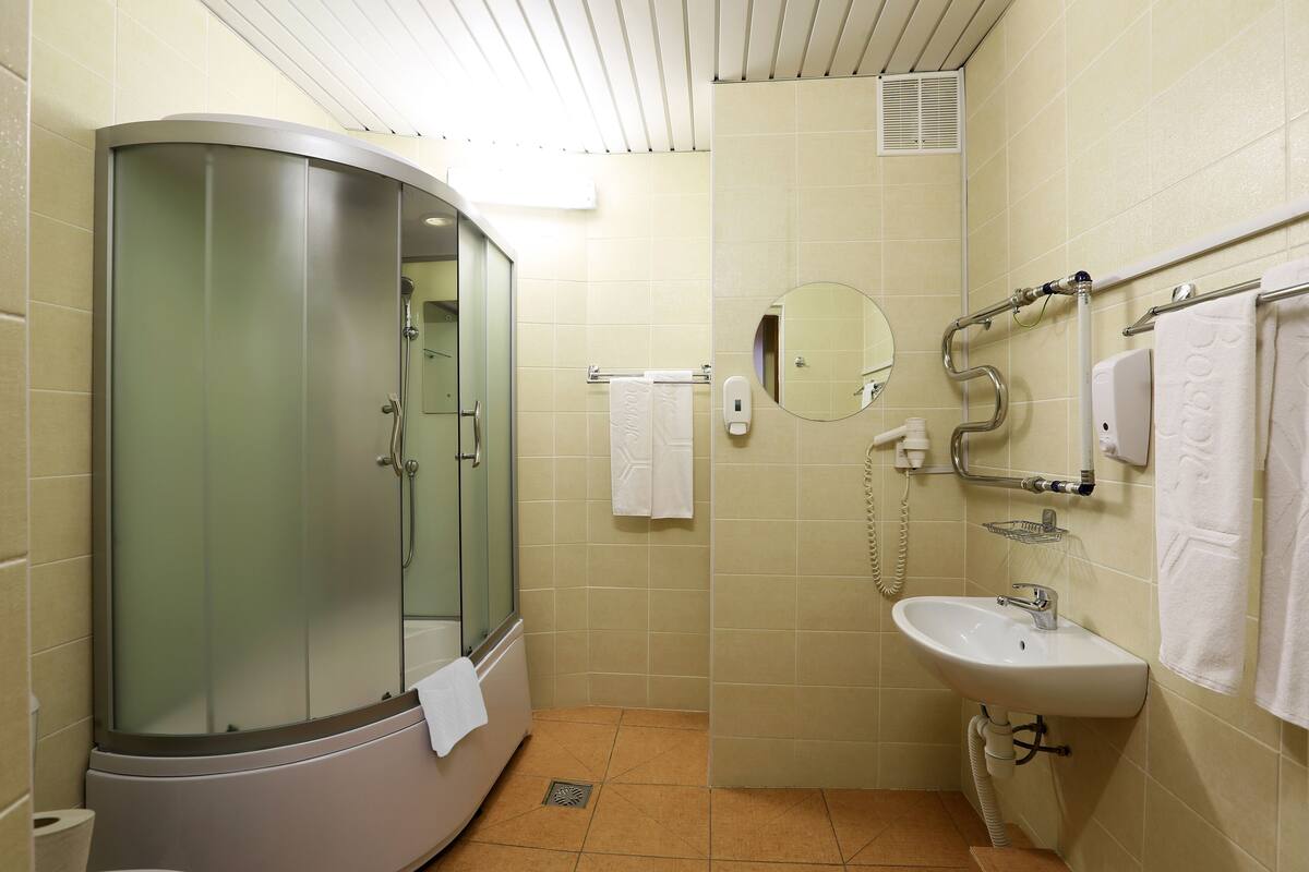 A bathroom with a glass-enclosed shower, a sink, a mirror, and a towel rack.