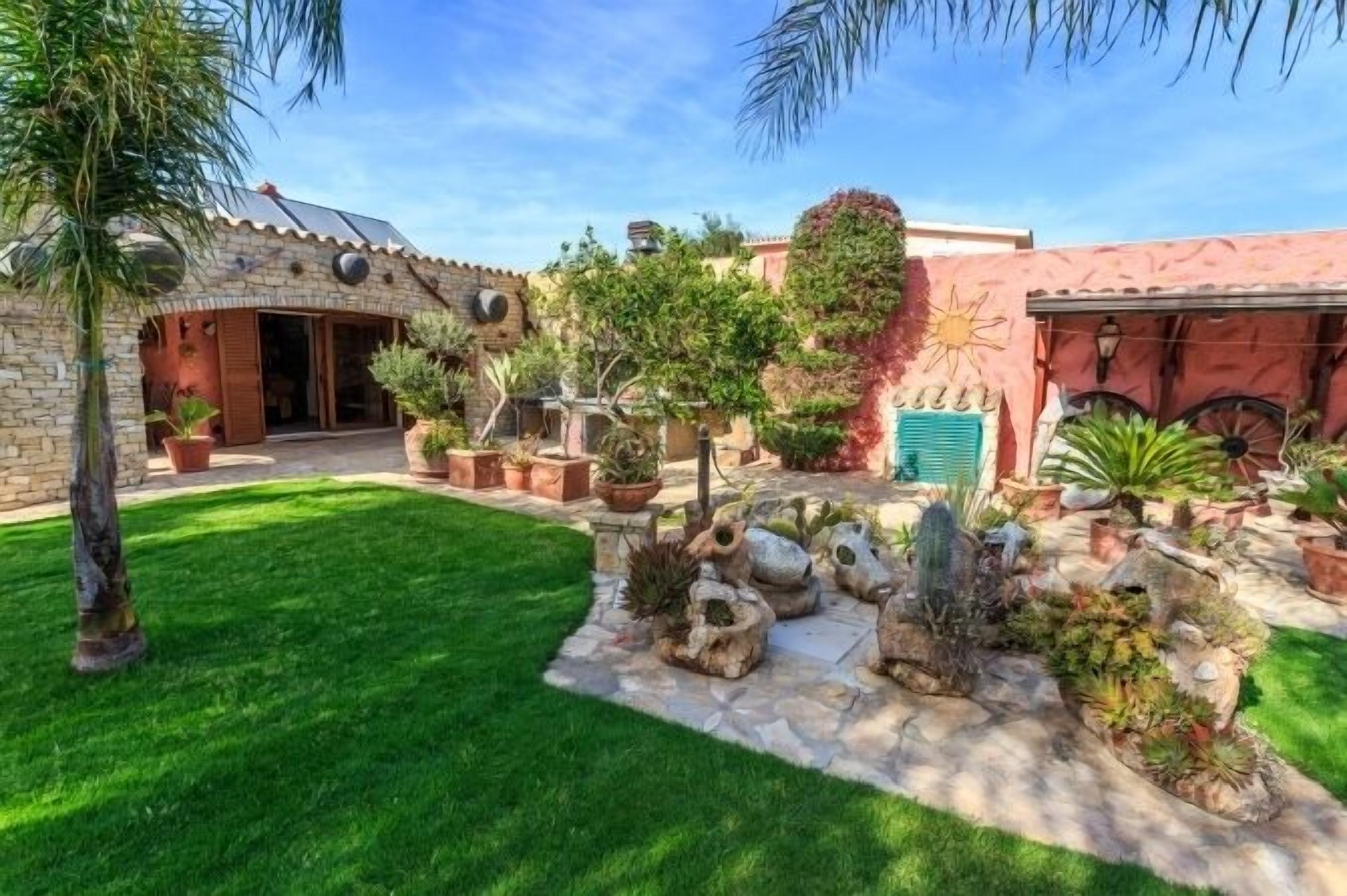 A courtyard with a stone pathway, potted plants, and a small rock garden.