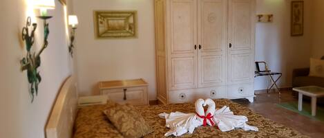 A bedroom with a large bed, a wardrobe, a nightstand, and a chair.