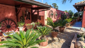 A courtyard with potted plants, a wooden table, and a rustic building with a tiled roof.