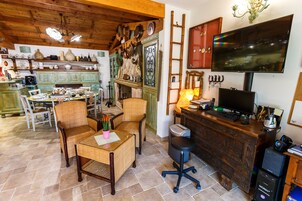 Una habitación acogedora con techo de madera, una mesa de comedor con sillas, un escritorio con computadora y un televisor montado en la pared.