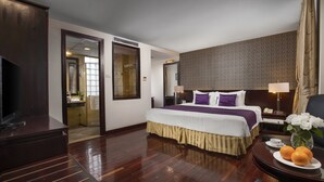 A hotel room with a large bed, a television, a desk with a lamp, and a vase with flowers. - TK123 Hanoi Hotel (Hanoi)