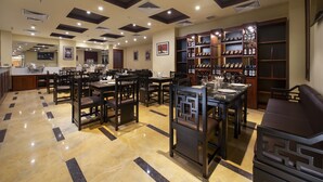 A restaurant with multiple dining tables and chairs, a wine rack, and a counter. - TK123 Hanoi Hotel (Hanoi)
