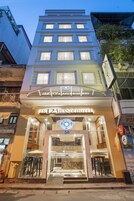 Un hotel con una entrada destacada, varios pisos y un cartel que indica que es un hotel.