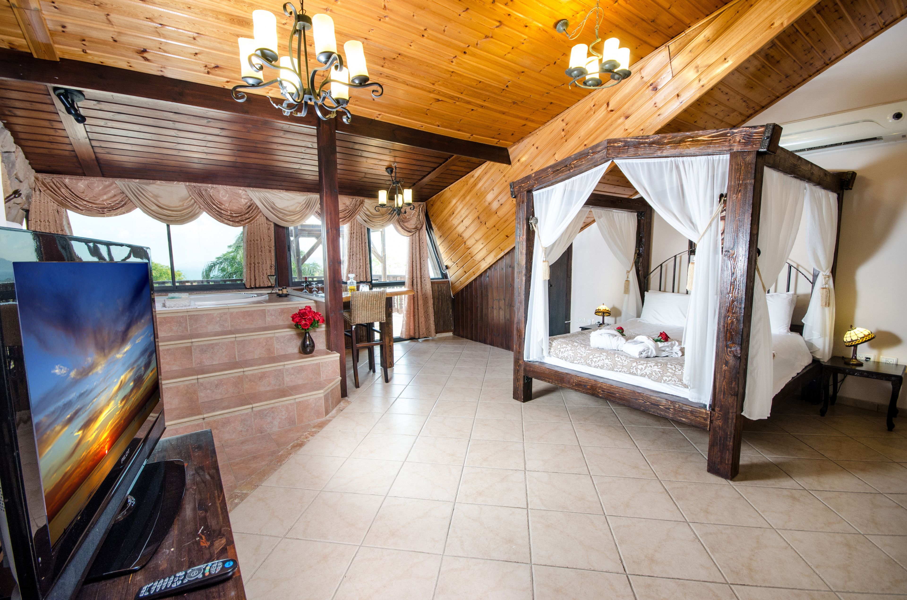 Une chambre à coucher avec un plafond en bois, un lit à baldaquin, une télévision et un escalier menant à un niveau supérieur.
