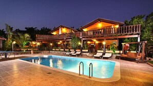 Een hotel met een zwembad, ligbedden en een houten terras.