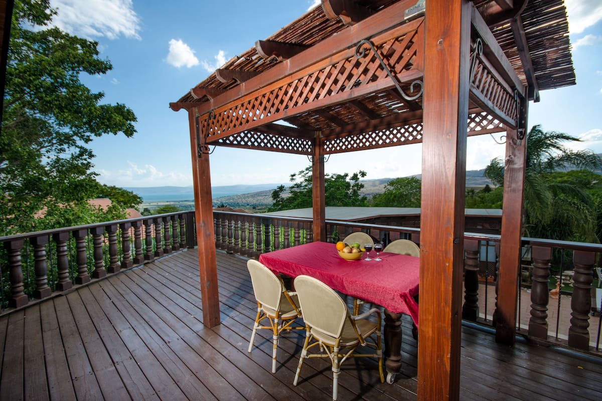 A wooden deck with a table and chairs, overlooking a scenic landscape.