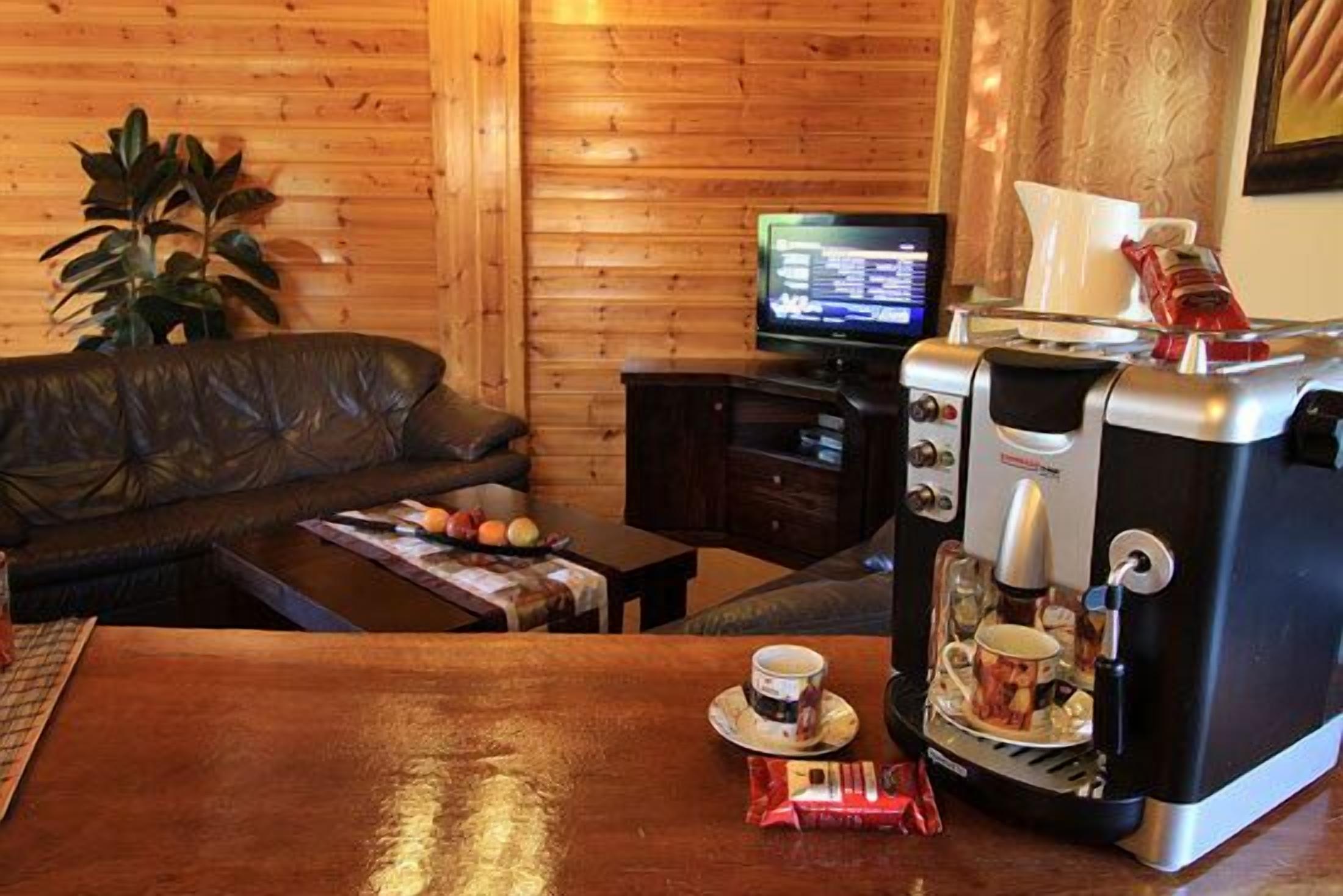 Une pièce chaleureuse avec un décor intérieur en bois, un canapé en cuir, une machine à café et un téléviseur posé sur un meuble en bois.