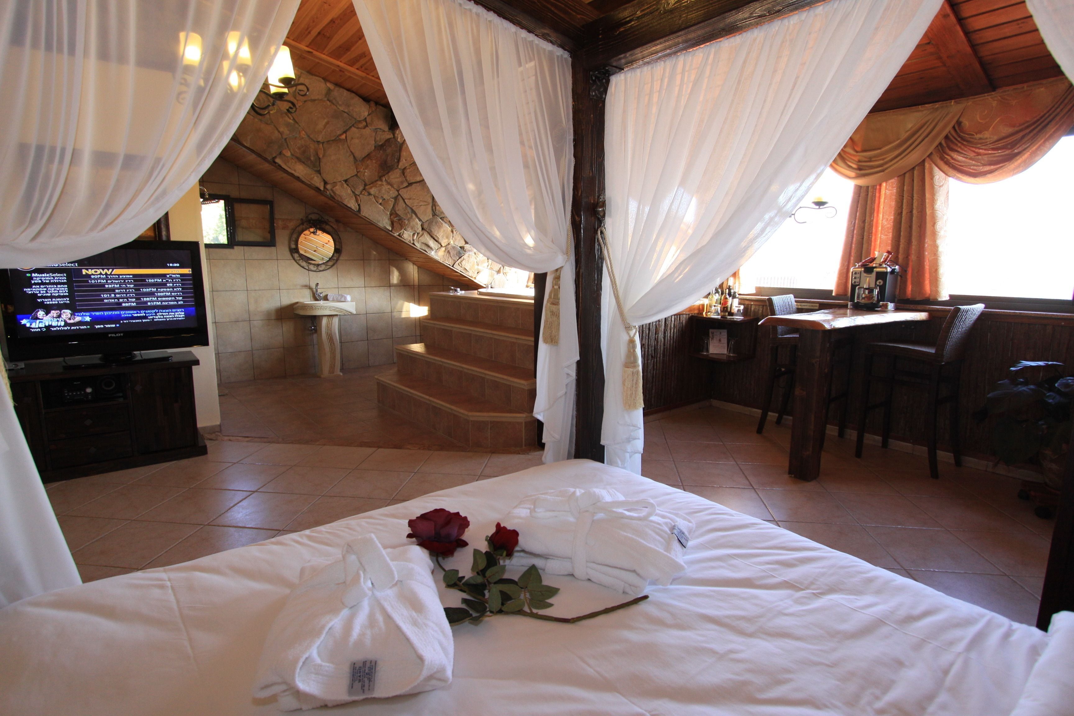A hotel room with a bed, a TV, a bathroom, and a dining area.
