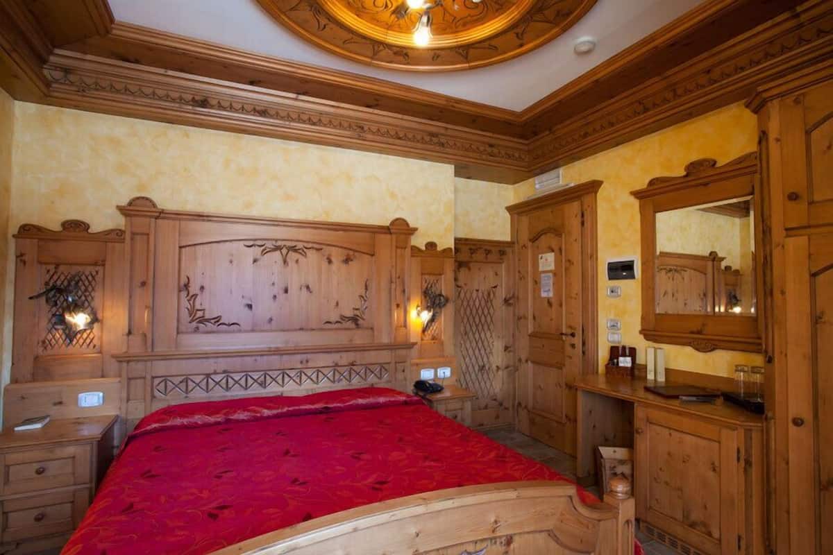 Un dormitorio de madera con una cama grande, cabecera de madera y un armario espejo.