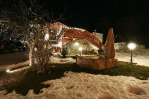 Paisaje nevado con una estructura de madera que incluye una escalera y una gran formación rocosa.
