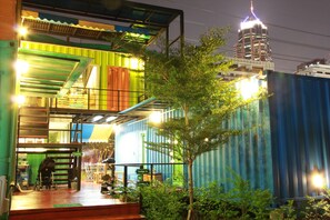 A multi-level structure with a staircase, outdoor seating, and a view of a cityscape. - WH Hostel (Bangkok)