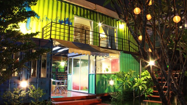 A two-story building with a balcony, a staircase, and a small outdoor seating area. - WH Hostel (Bangkok)