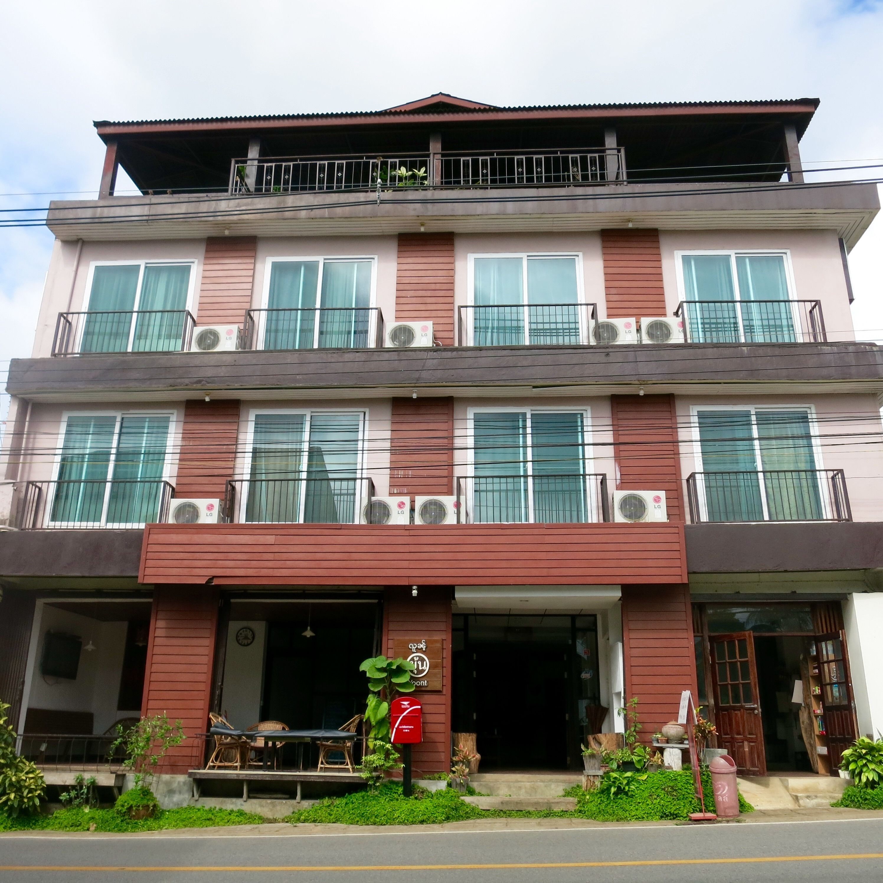 A multi-story building with balconies, air conditioning units, and a front entrance with outdoor seating.