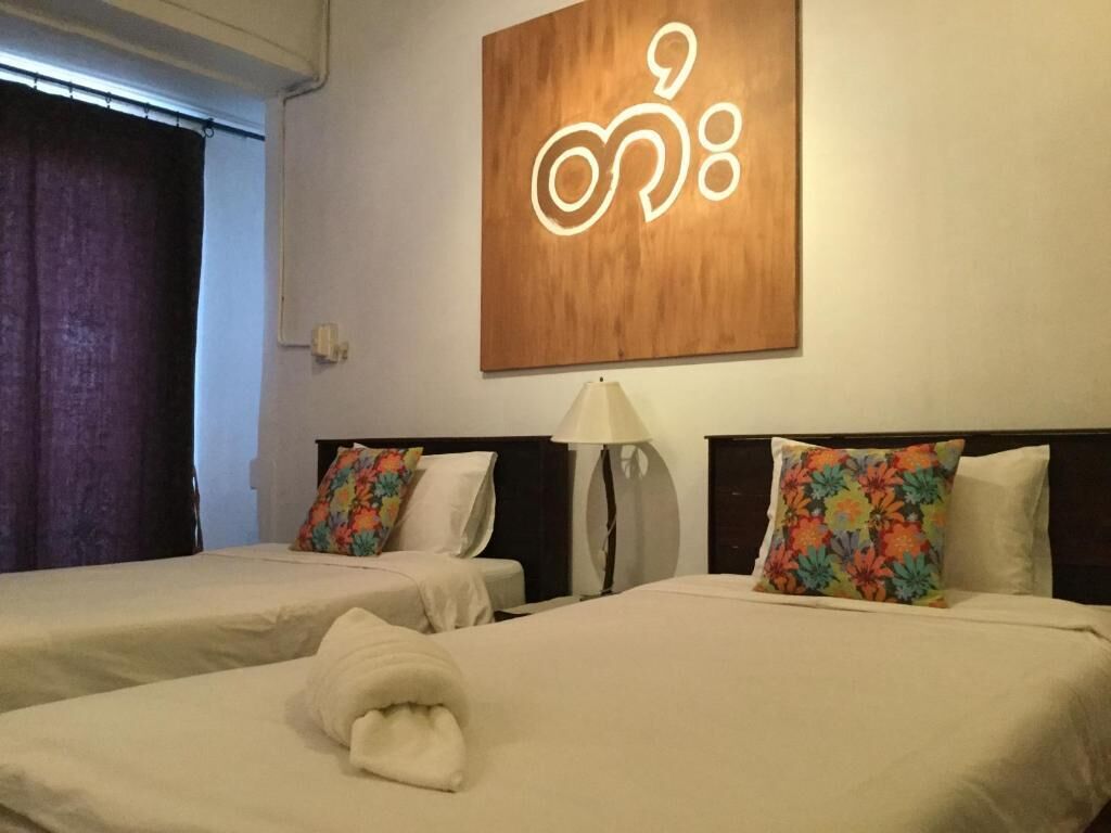 Habitación de hotel con dos camas, cada una con un cojín floral, una lámpara y un cartel en la pared.
