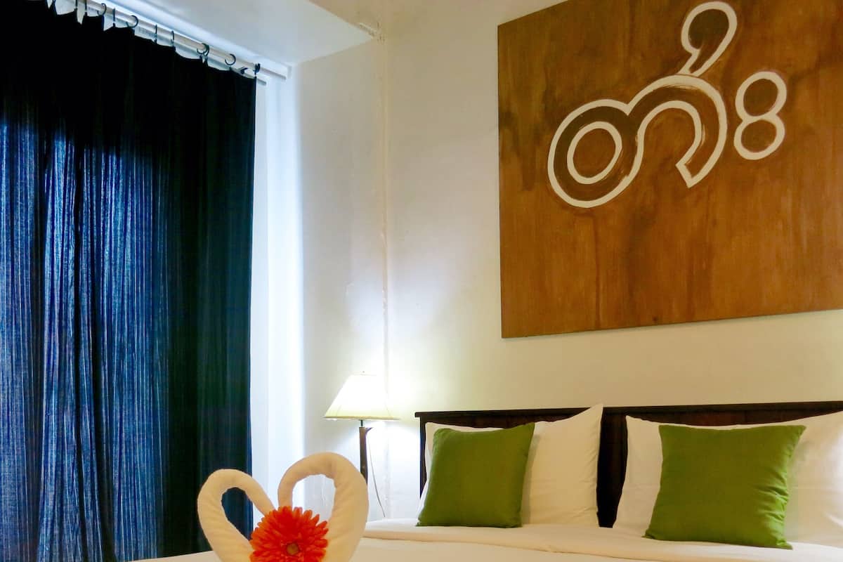 A hotel room with a bed, a wall-mounted artwork, and a window with curtains.