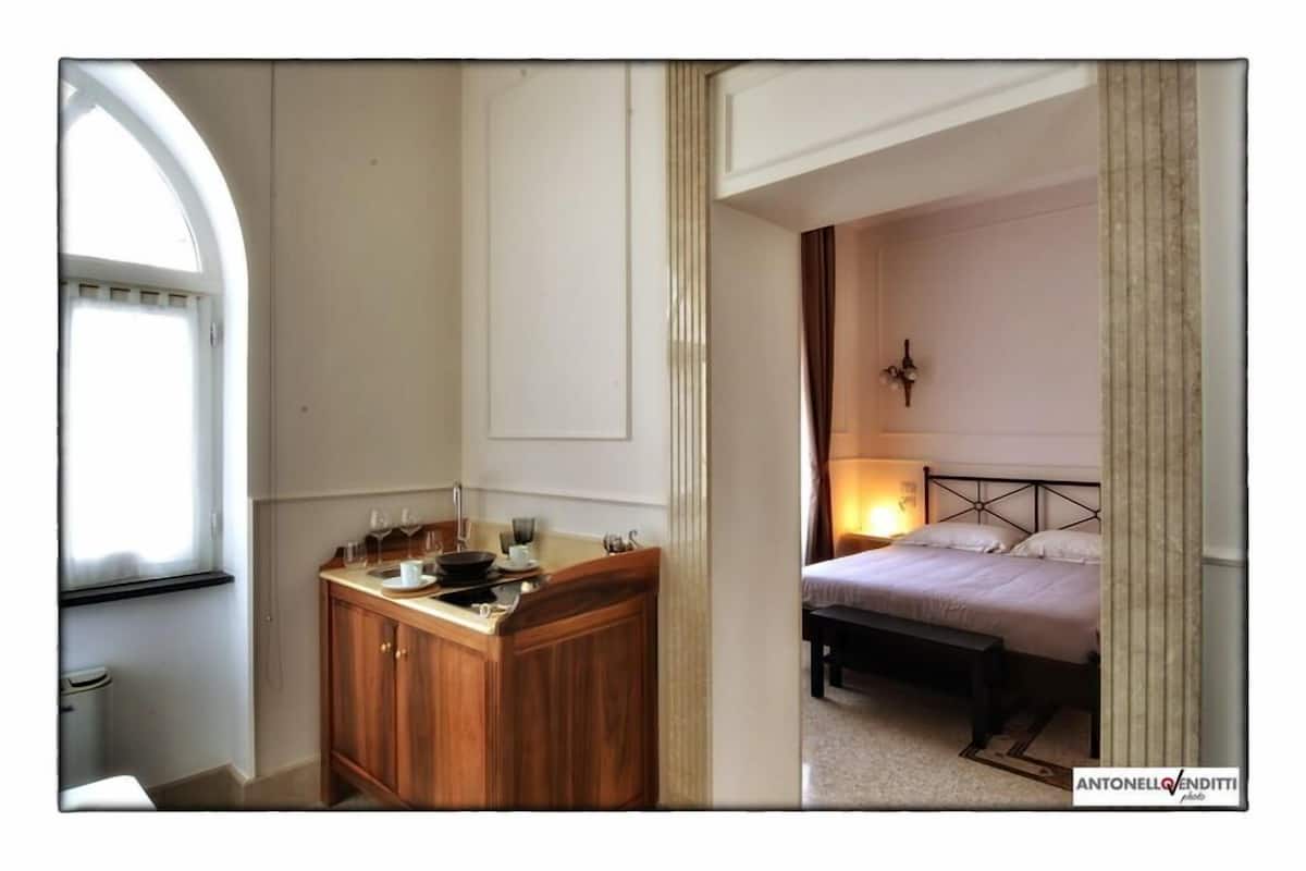 Una habitació amb escriptori de fusta, llit i finestra.