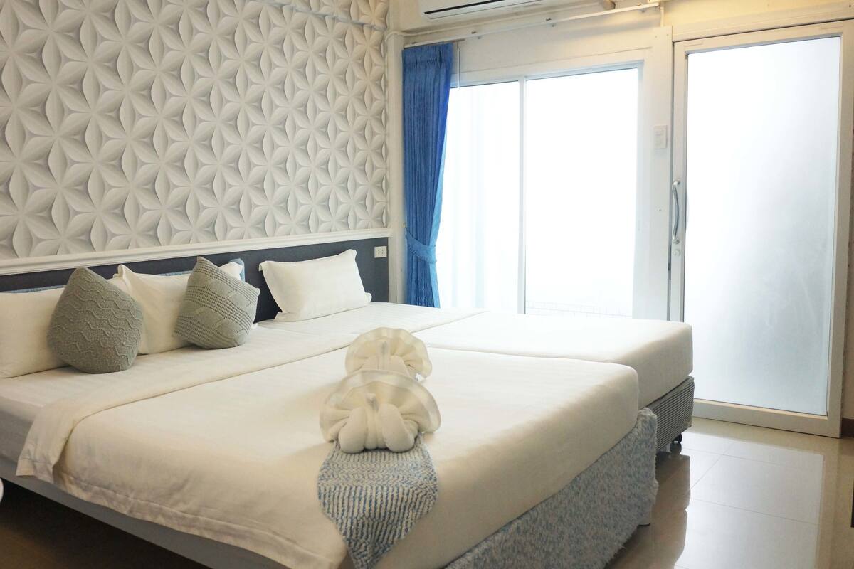 A hotel room with a large bed, a round table, and a patterned wall.