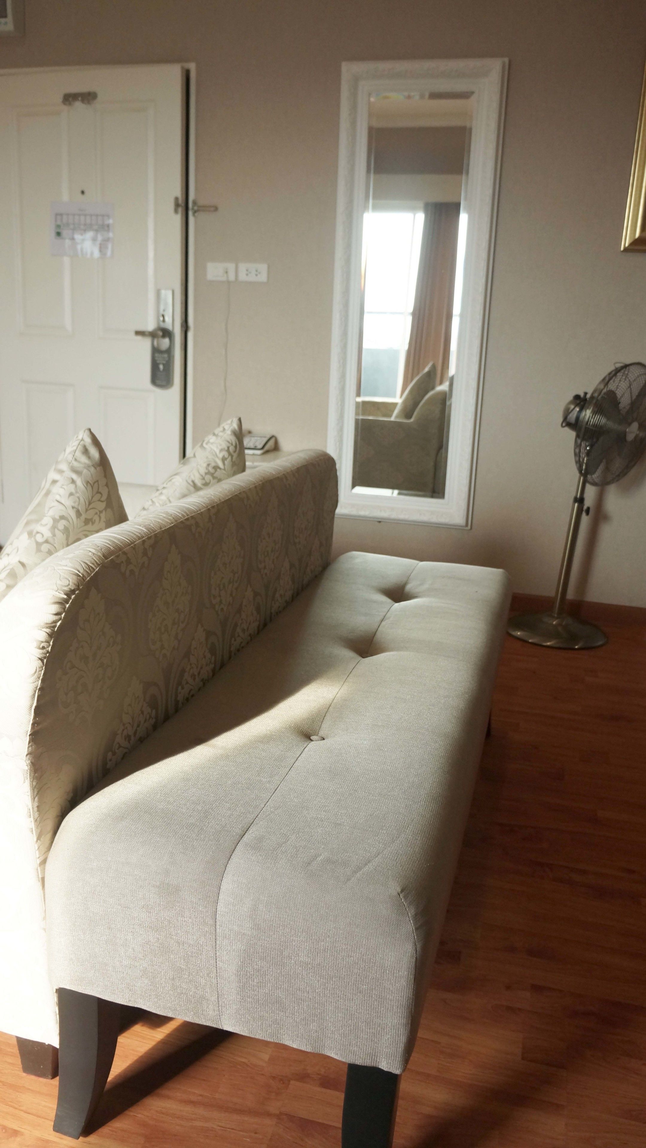 A room with a sofa, a door, a window, and a floor lamp.
