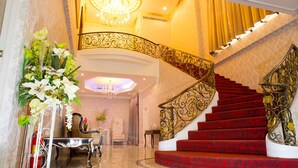 A grand staircase with red carpet and ornate metal railings, leading to an upper floor. - Westgate Residence Hotel (Bang Yai)