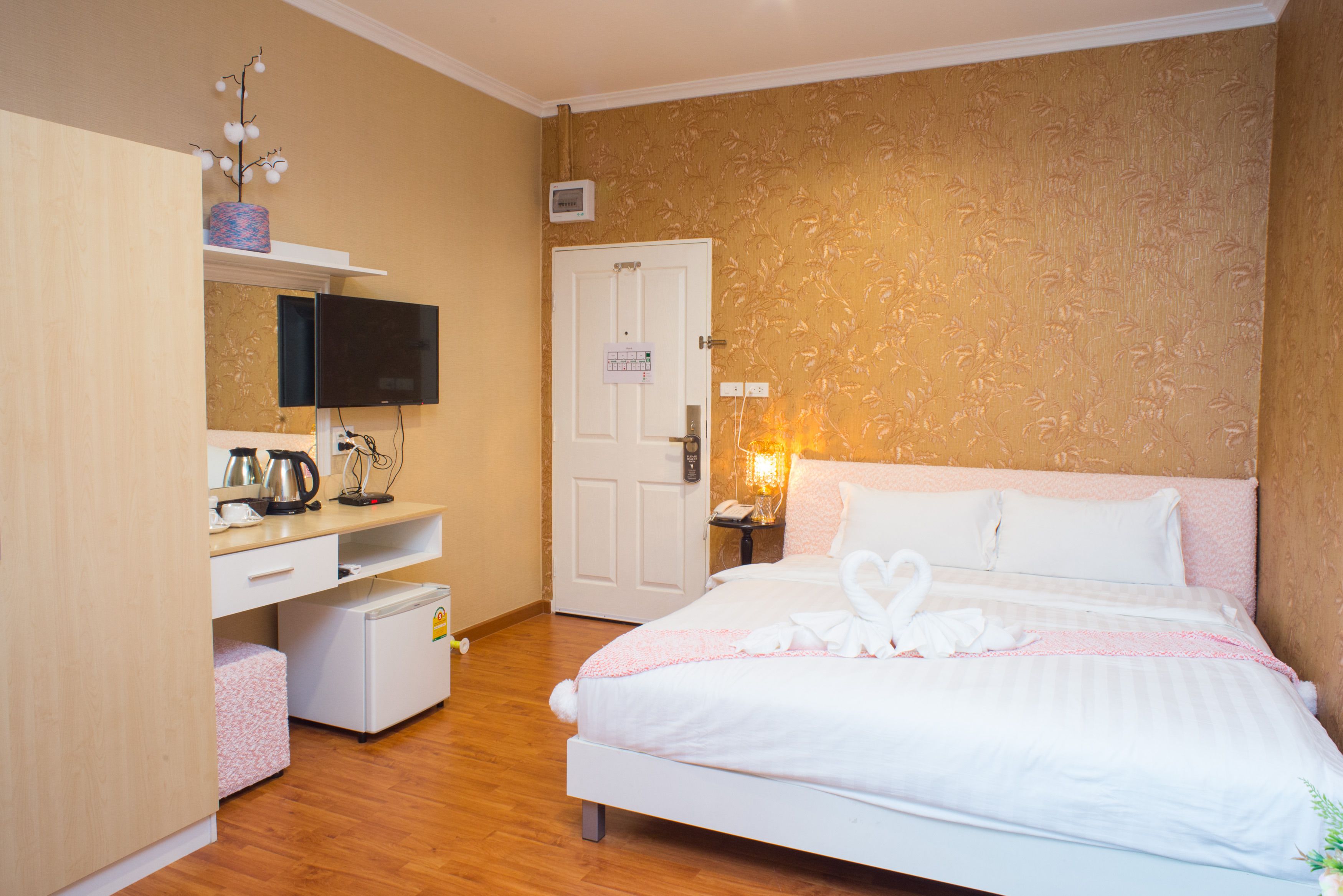 Une chambre d’hôtel équipée d’un lit, d’une télévision, d’un bureau avec une bouilloire, d’un petit réfrigérateur et d’une porte à clé.