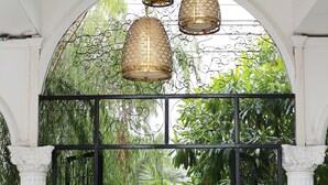 A covered garden area with a checkered floor, metal gate, and hanging lamps. - Westgate Residence Hotel (Bang Yai)