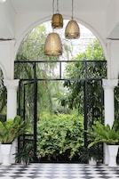 Uma área de jardim coberta com piso xadrez, portão de metal e luminárias pendentes.
