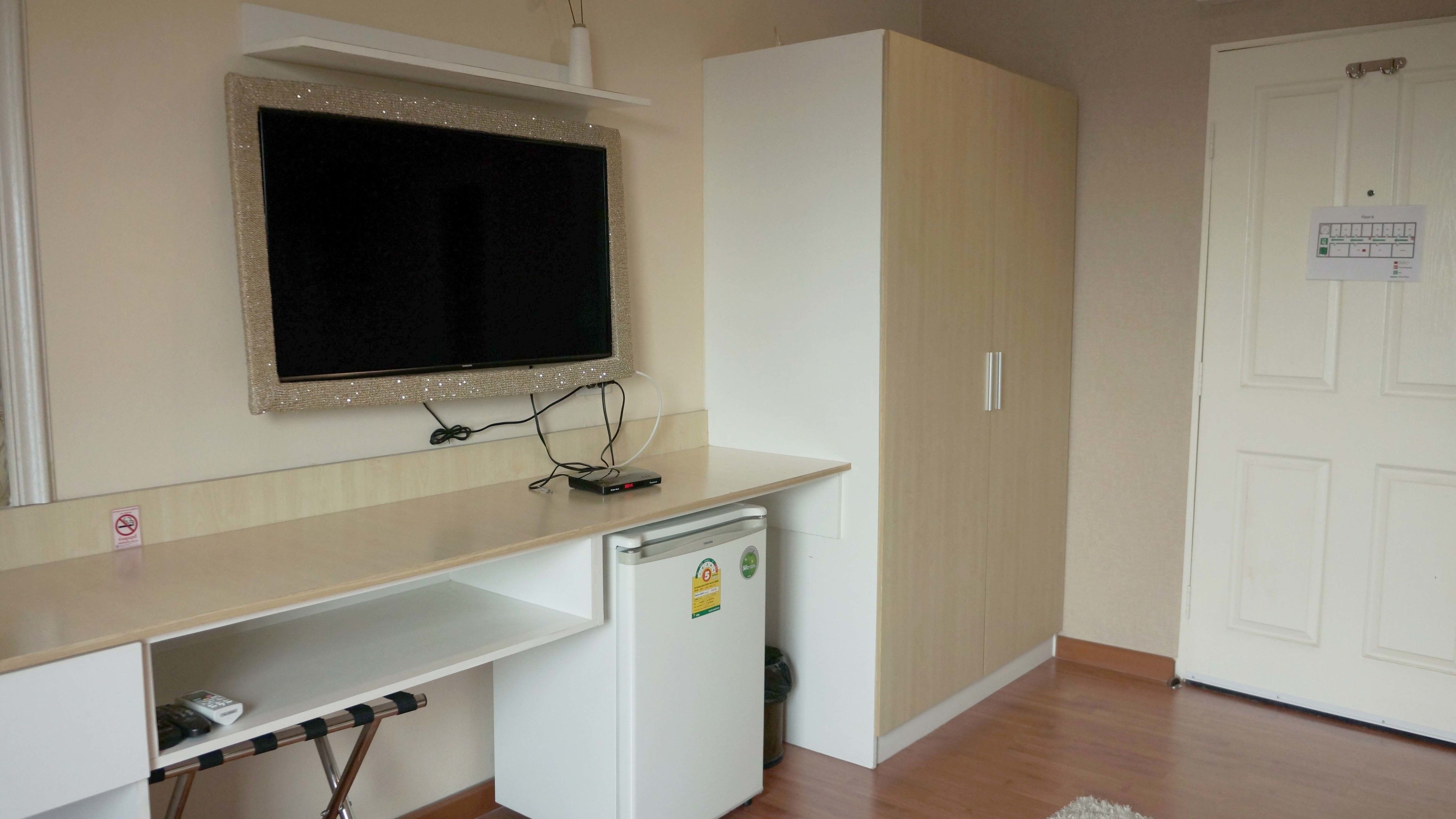 A compact room with a kitchenette, a small refrigerator, a microwave, a sink, and a white door with a notice.