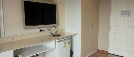 A compact room with a kitchenette, a small refrigerator, a microwave, a sink, and a white door with a notice.