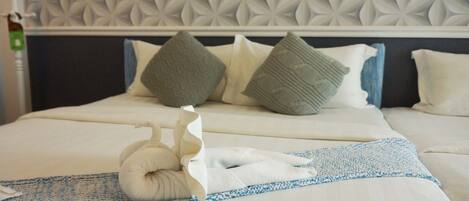 A neatly made bed with a patterned headboard, pillows, and a folded towel on a blue and white striped blanket.
