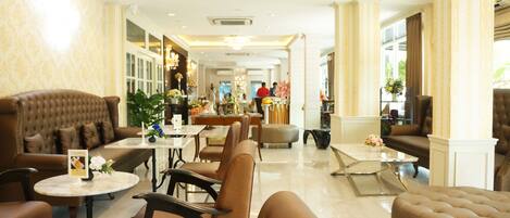 A spacious lobby with leather sofas, a marble coffee table, and a reception desk.