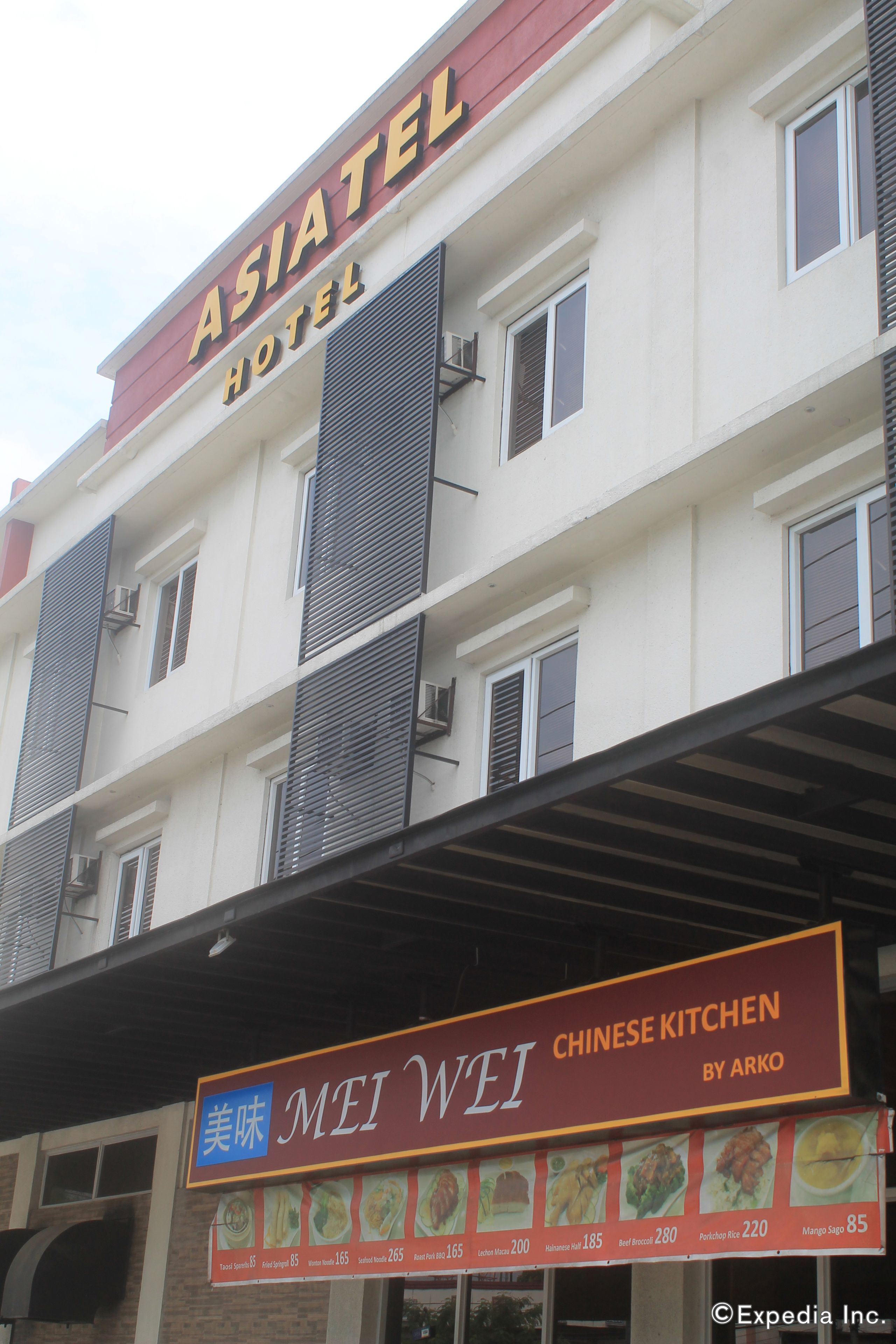 A hotel with a sign for 'ASIATEL HOTEL' and a Chinese restaurant named 'MEI WEI' below it.