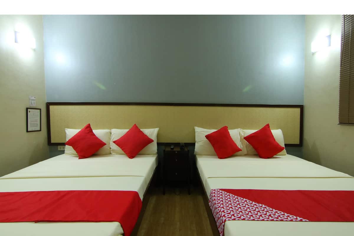 A hotel room with two beds, each with red and white bedding, a headboard, and a nightstand.