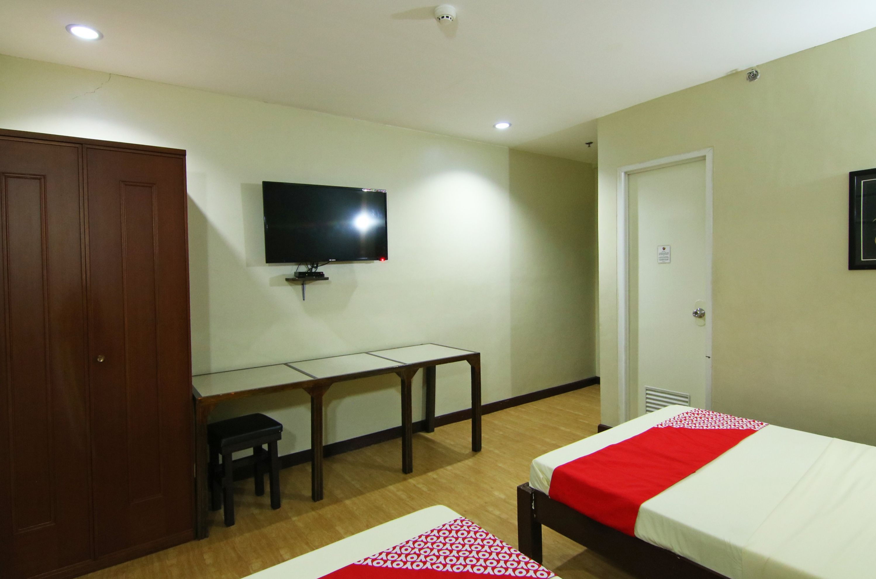 A hotel room with a bed, a desk, a chair, a TV, and a wardrobe.