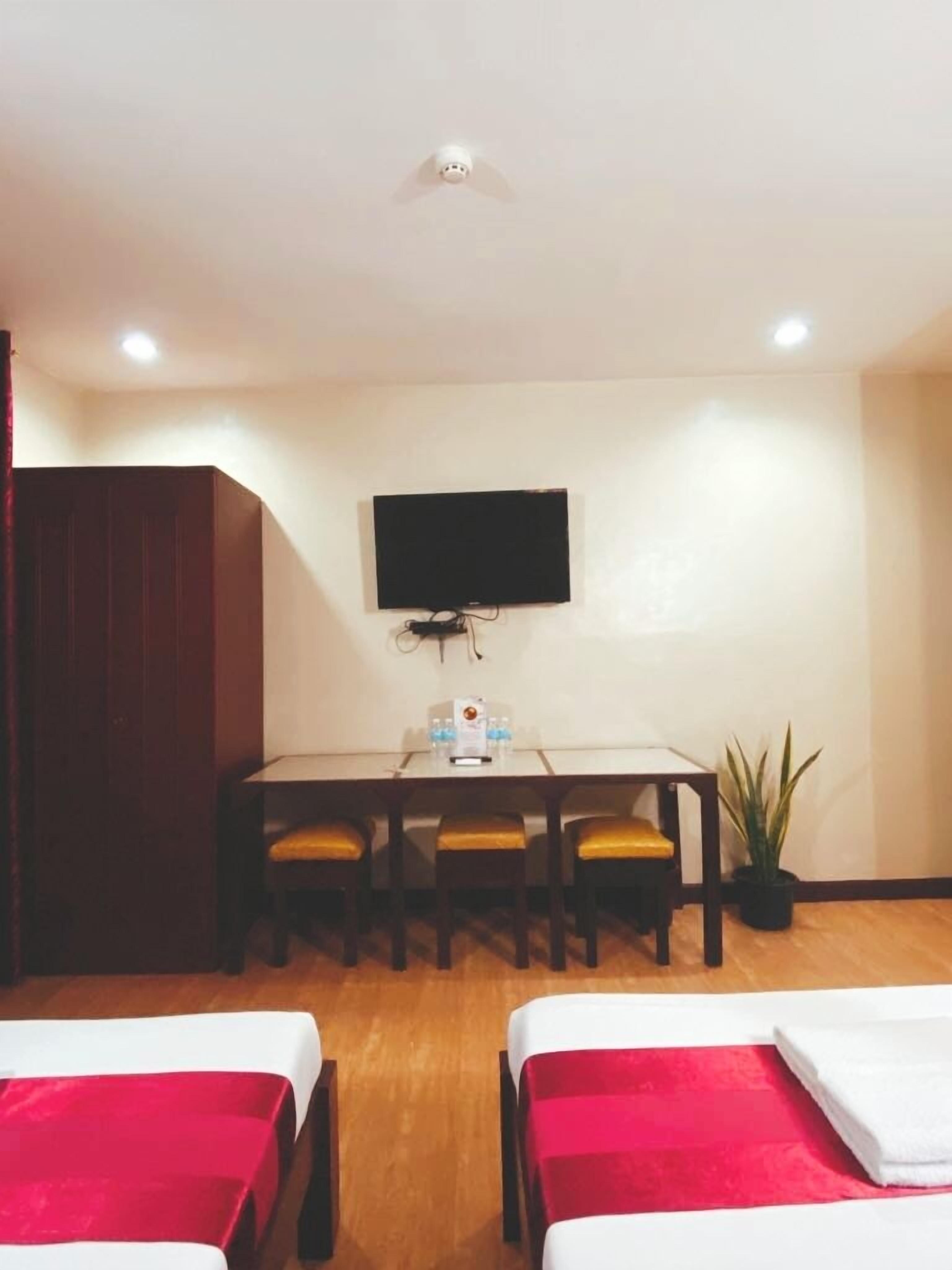 Une chambre d’hôtel avec un lit, un bureau et une chaise, une télévision et une plante en pot.