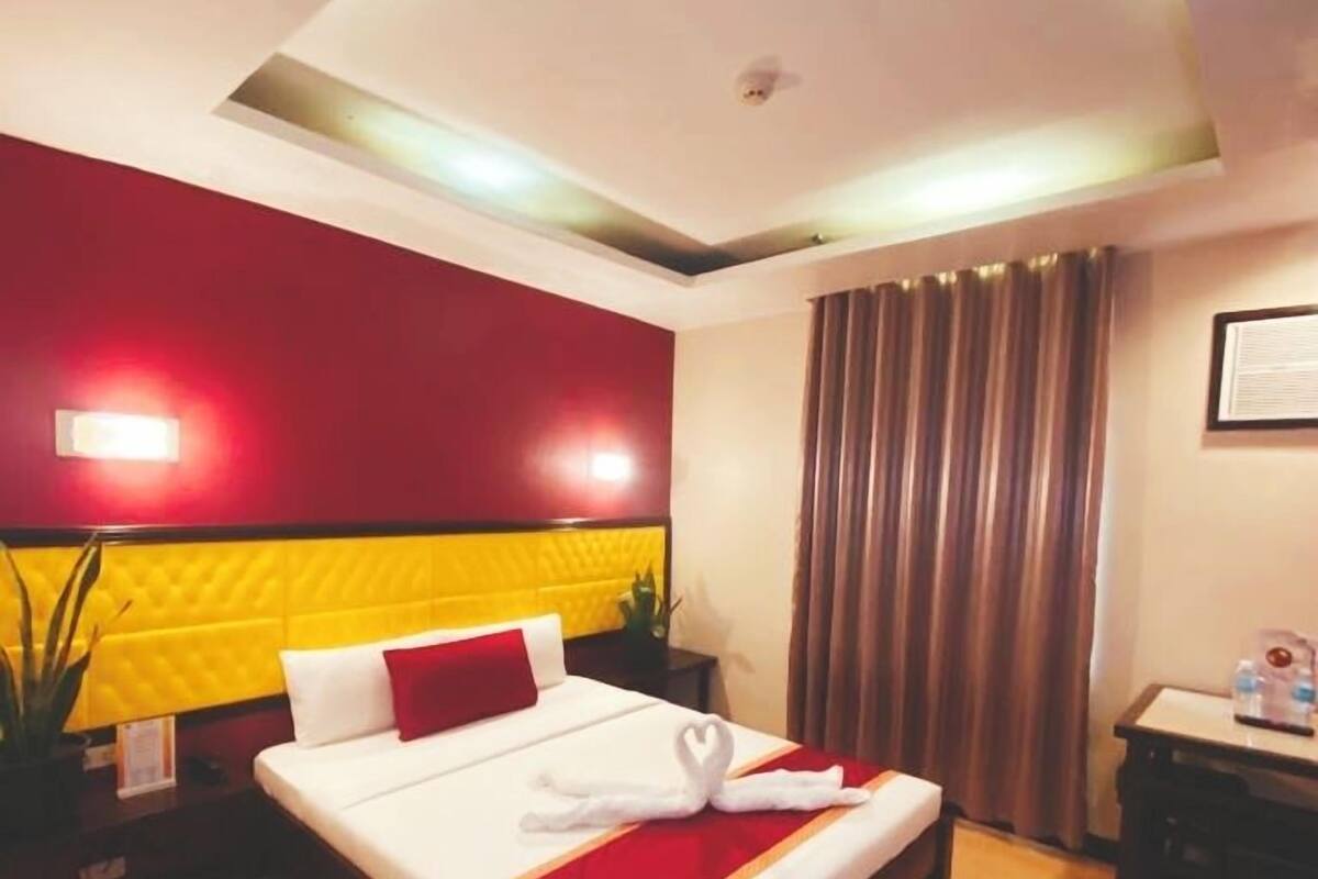 A hotel room with a bed, a desk, and a nightstand.