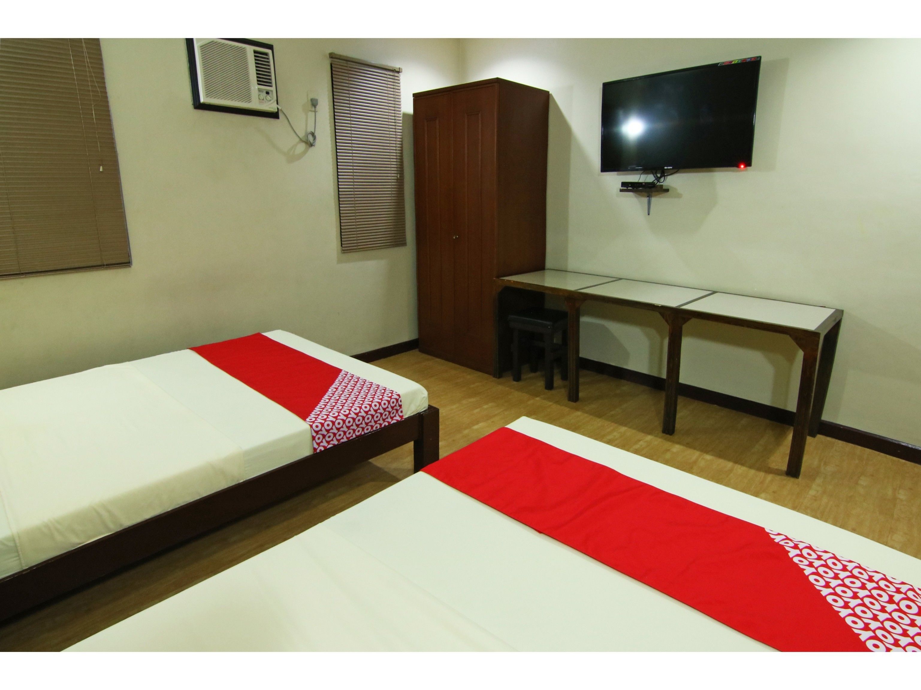 A room with two beds, a desk, a television, and a wardrobe.