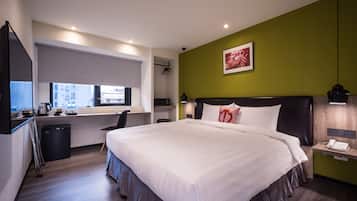 A modern hotel room with a large bed, a desk, and a window with a city view.