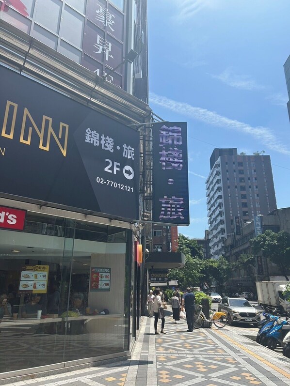 A street view with a building featuring a sign for '2F' and a contact number. - Goldinn Hotel (Taipei)