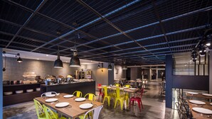 A modern restaurant with high ceilings, exposed beams, and a mix of colorful and white chairs. - Goldinn Hotel (Taipei)