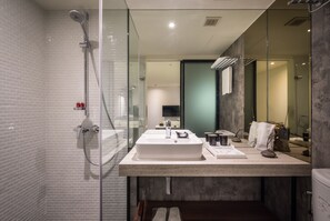 A modern bathroom with a glass shower enclosure, a sink with a mirror, and a vanity with a towel rack. - Goldinn Hotel (Taipei)