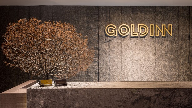 A reception desk with a large tree and the name 'GOLDIN' in illuminated letters on the wall. - Goldinn Hotel (Taipei)