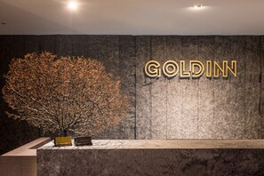 A reception desk with a large tree and the name 'GOLDIN' in illuminated letters on the wall. - Goldinn Hotel (Taipei)