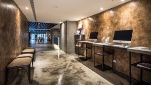 A modern reception area with a long counter, two computer stations, and a seating area with benches. - Goldinn Hotel (Taipei)