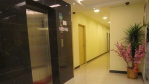 An elevator with a red mat, a welcome mat, a potted plant, and a hallway with a door. - City Comfort Inn Puchong (Puchong)