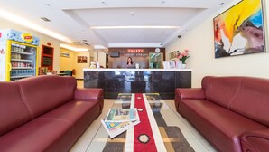 A reception area with a counter, two red sofas, a magazine on the floor, and a vending machine. - City Comfort Inn Puchong (Puchong)
