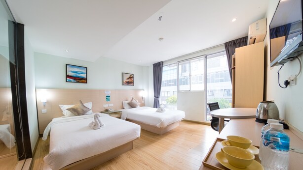 A hotel room with two beds, a dining table, a kettle, and a tray with cups and a bottle. - City Comfort Inn Puchong (Puchong)