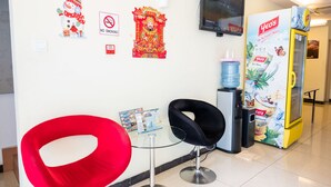 A reception area with a glass table, two chairs, a water dispenser, a vending machine, and wall decorations including a no-smoking sign and a cultural figure. - City Comfort Inn Puchong (Puchong)