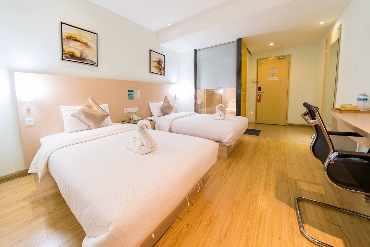 A hotel room with two beds, a desk, and a chair.