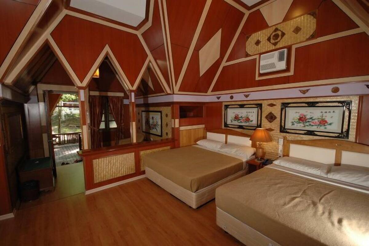 A room with two beds, wooden walls, and a view of the outdoors.